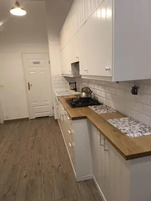 a kitchen with white cabinets and a counter top at wawel hostel in Kraków