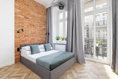 a bedroom with a bed and a brick wall at Kazimierz - Balcony Apartment- Starowiślna 41 in Kraków
