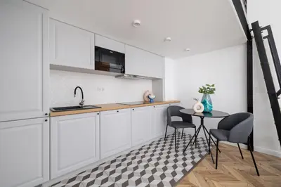a kitchen with white cabinets and a table and chairs at Kazimierz - Balcony Apartment- Starowiślna 41 in Kraków