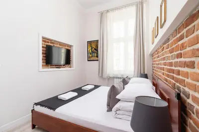 a bedroom with a bed and a brick wall at Two bedroom apartment - Starowiślna 36 in Kraków