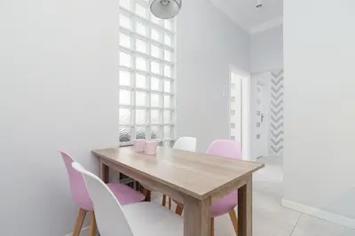 a dining room with a wooden table and pink chairs at Two bedroom apartment - Starowiślna 36 in Kraków