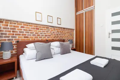 a bedroom with a white bed with a brick wall at Two bedroom apartment - Starowiślna 36 in Kraków