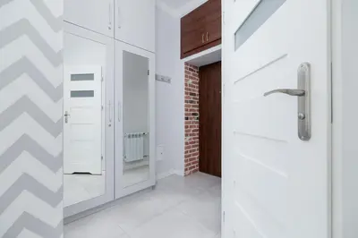 a hallway with a white door and a brick wall at Two bedroom apartment - Starowiślna 36 in Kraków
