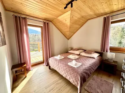 a bedroom with a bed and a large window at Domek SAMI SWOI in Zawoja