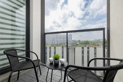 a balcony with two chairs and a table on a balcony at Mogilska Apartments with Parking near TAURON Arena Kraków by Noclegi Renters in Kraków