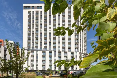 a tall white building with trees in front of it at Mogilska Apartments with Parking near TAURON Arena Kraków by Noclegi Renters in Kraków