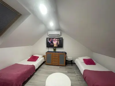 a attic room with two beds and a tv at APARTAMENT KRÓLEWSKI CENTRUM NIEPOŁOMICE in Niepołomice