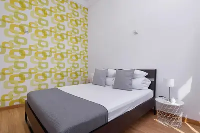 a bedroom with a bed and a yellow and white wall at 1-Bedroom Apartment - Brodzińskiego 3 - Podgórze in Kraków