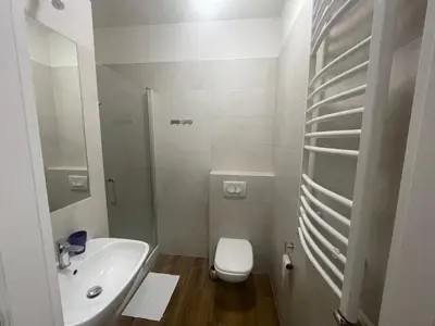 a white bathroom with a toilet and a sink at Apartamenty 3 Kraków Podgórze in Kraków