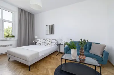 a white bedroom with a bed and a blue couch at 1-Bedroom Apartment - Długa 65 in Kraków
