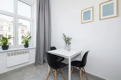 a white table and chairs in a white room with a window at 1-Bedroom Apartment - 65 Długa Street in Kraków