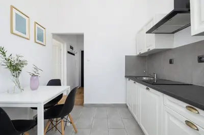 a kitchen with white cabinets and a white table and chairs at 1-Bedroom Apartment - 65 Długa Street in Kraków