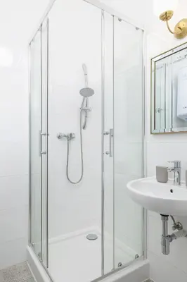 a white bathroom with a shower and a sink at 1-Bedroom Apartment - 65 Długa Street in Kraków