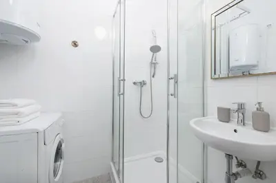 a white bathroom with a shower and a sink at 1-Bedroom Apartment - 65 Długa Street in Kraków