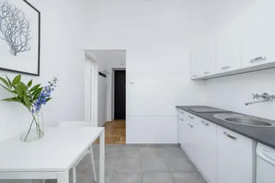 a white kitchen with a sink and a table at 1-Bedroom Apartment - Długa 65 street in Kraków