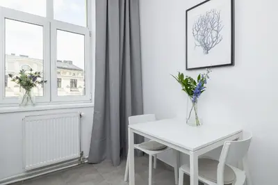 a white table and chairs in a white room with a window at 1-Bedroom Apartment - Długa 65 street in Kraków