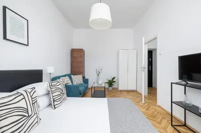 a white room with a bed and a blue couch at 1-Bedroom Apartment - Długa 65 street in Kraków