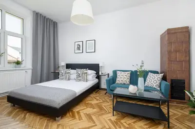 a bedroom with a bed and a blue chair at 1-Bedroom Apartment - Długa 65 street in Kraków