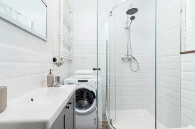 a white bathroom with a washing machine and a glass shower at Kazimierz District - Starowislna 43 in Kraków