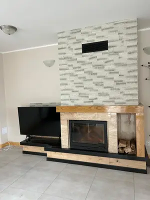 a fireplace in a living room with a stone wall at Dom wypoczynkowy z widokiem na LUBAŃ in Ochotnica Dolna