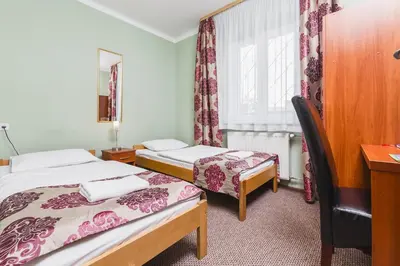 a room with two beds and a desk and a window at Hostel Biały Dom in Kraków