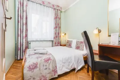 a bedroom with a bed with a chair and a desk at Hostel Biały Dom in Kraków