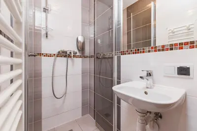 a white bathroom with a shower and a sink at Hostel Biały Dom in Kraków