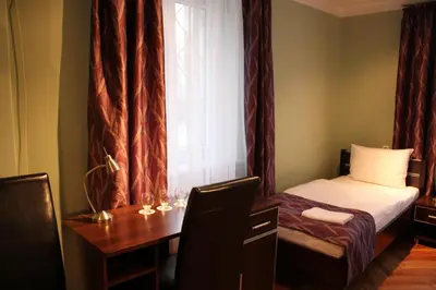 a bedroom with a bed and a desk and a window at Hostel Biały Dom in Kraków