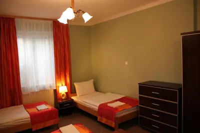 a small bedroom with two beds and a dresser at Hostel Biały Dom in Kraków