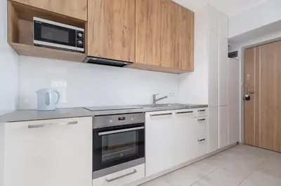 a white kitchen with a microwave and a stove at One bedroom apartment Kalwaryjska 34 street in Kraków