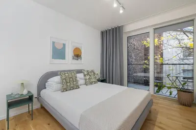 a bedroom with a white bed and a large window at Kalwaryjska 34 street Studio with balcony in Kraków