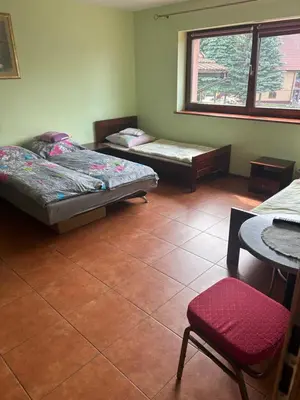 a room with two beds and a table and a window at Grojecka Ostoja in Grojec