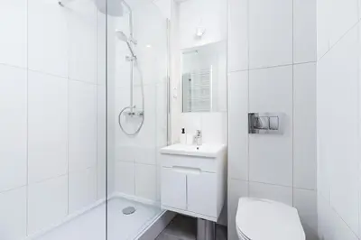 a white bathroom with a shower and a sink at Apartment with balcony - Paulinska 8 street in Kraków