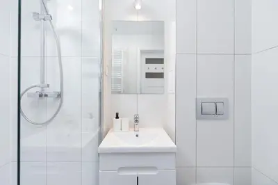 a white bathroom with a sink and a shower at Apartment with balcony - Paulinska 8 street in Kraków