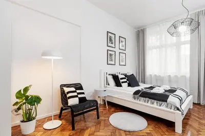 a white bedroom with a bed and a chair at Kazimierz District - Paulińska 18 Street in Kraków