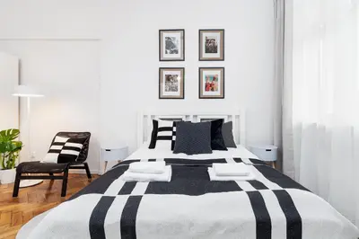 a bedroom with a black and white bed and a chair at Kazimierz District - Paulińska 18 Street in Kraków
