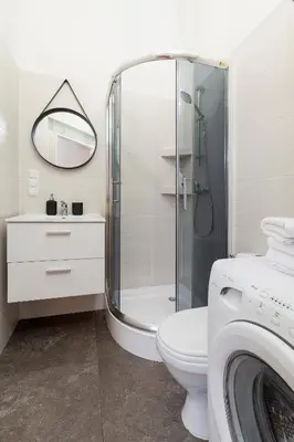 a bathroom with a shower and a toilet and a washing machine at Kazimierz District - Paulińska 18 Street in Kraków