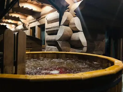 a large tub filled with water next to a stone wall at Domek na Wierchu Bukowiny in Załuczne