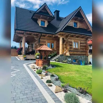 a large log house with a black roof at Domek na Wierchu Bukowiny in Załuczne