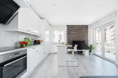 a kitchen with white cabinets and a table with a chair at Apartament Chrobrego Wieliczka 2 in Wieliczka