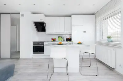 a white kitchen with white cabinets and white chairs at Apartament Chrobrego Wieliczka 2 in Wieliczka