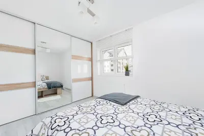 a white bedroom with a bed and a window at Apartament Chrobrego Wieliczka 2 in Wieliczka