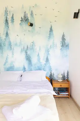 a bedroom with a bed with a forest mural on the wall at Strumienna Apartament in Kraków