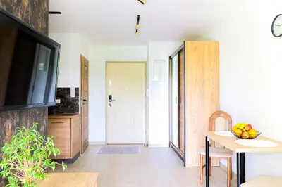 a living room with a television and a dining room table at Strumienna Apartament in Kraków
