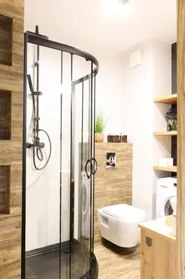 a bathroom with a glass shower with a toilet at Strumienna Apartament in Kraków