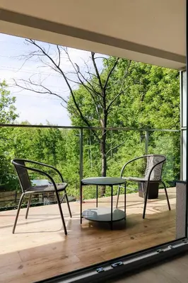 two chairs and a table on a deck with a window at Strumienna Apartament in Kraków
