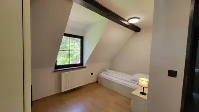 a small attic room with a bed and a window at Domek Zacisze Zator Graboszyce in Graboszyce