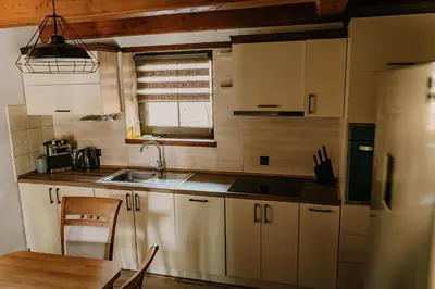 a kitchen with white cabinets and a sink and a table at Domek Zacisze Zator Graboszyce in Graboszyce
