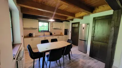 a kitchen with a wooden table and black chairs at Domek Zacisze Zator Graboszyce in Graboszyce
