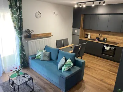 a living room with a blue couch and a kitchen at EM Room in Kraków